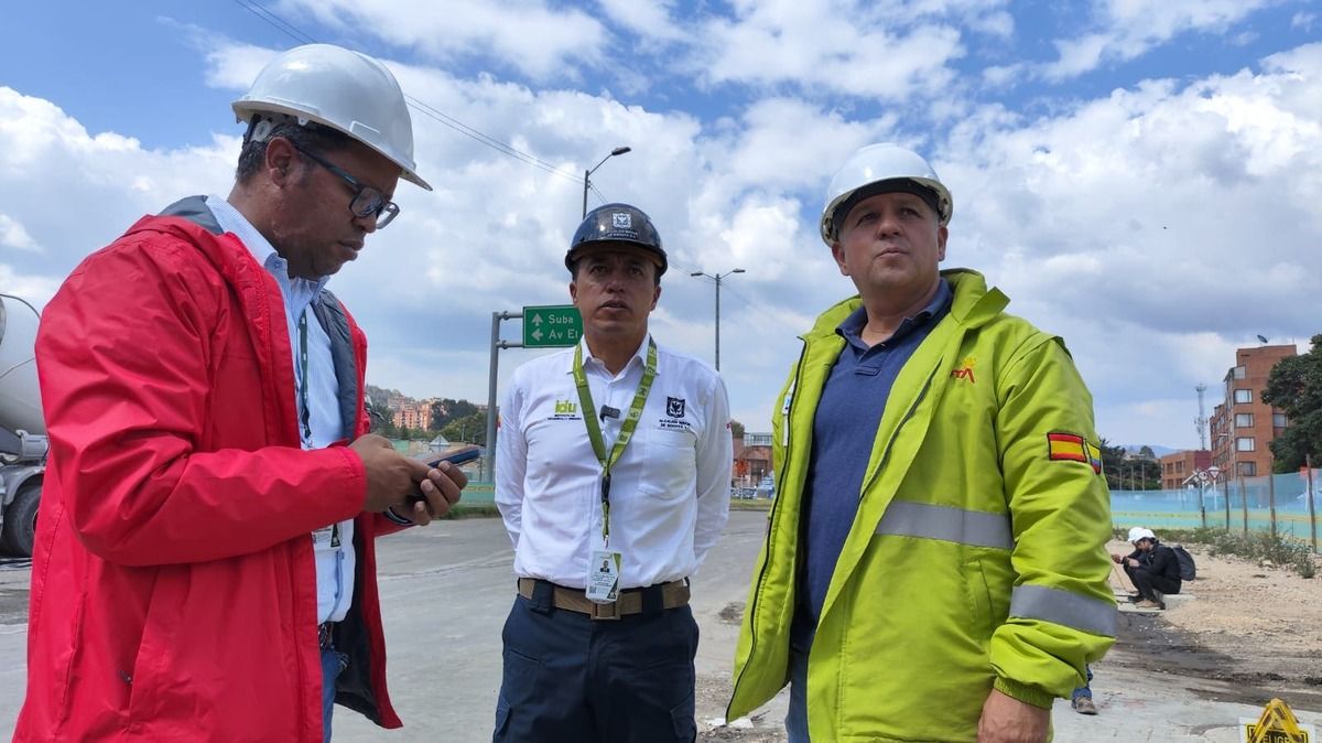 El director del IDU, Orlando Molano, mira la obra de construcción del puente de la calle 127 junto a dos personas de su equipo de trabajo